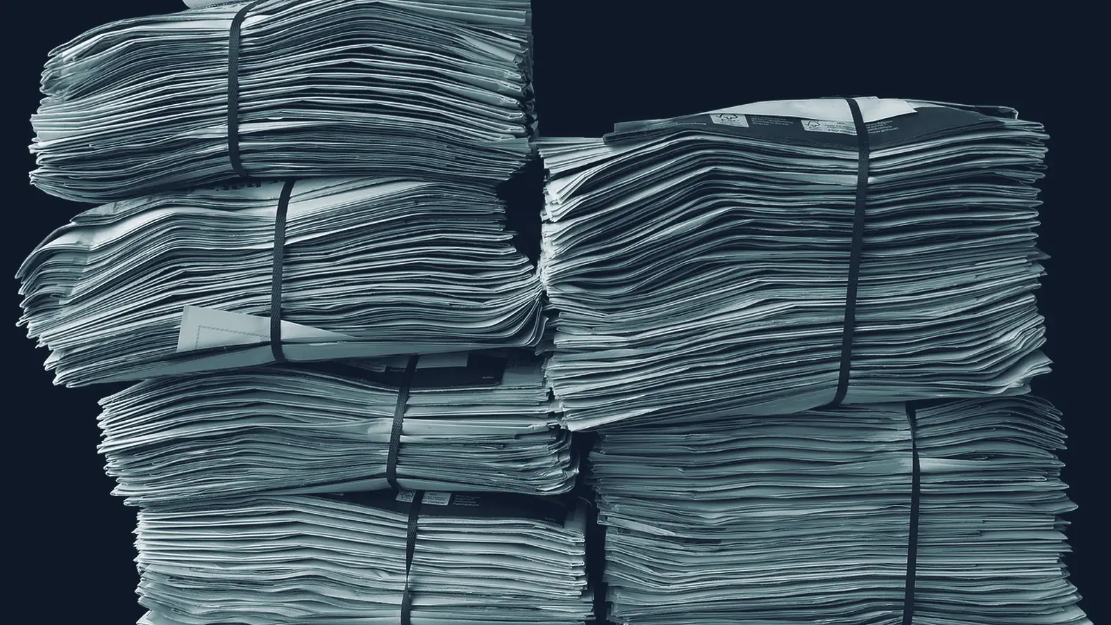 Mehrere gebündelte Stapel Papier vor schwarzem Hintergrund, mit Bändern zusammengehalten