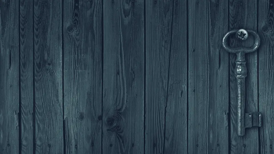 Ein alter Schlüssel hängt an einer Wand aus Holzbrettern